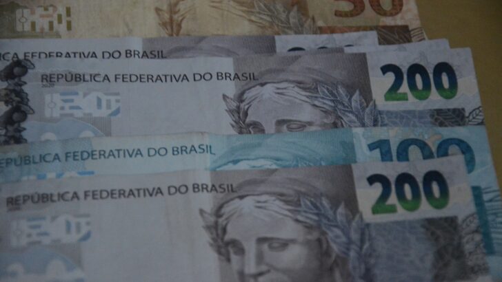 Cédulas e moedas de real, em imagem sobre finanças