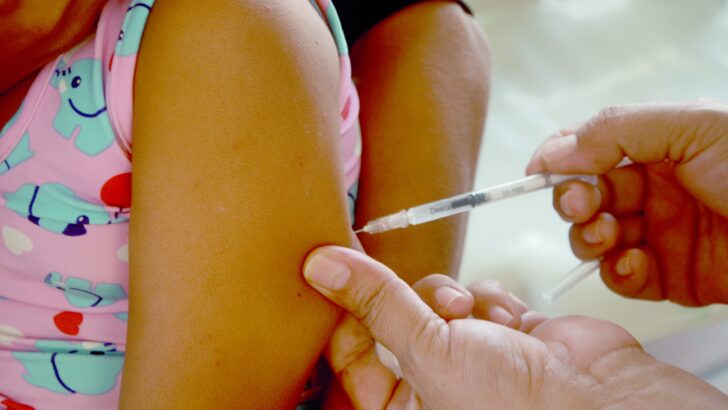 Profissional aplica vacina no braço de uma criança