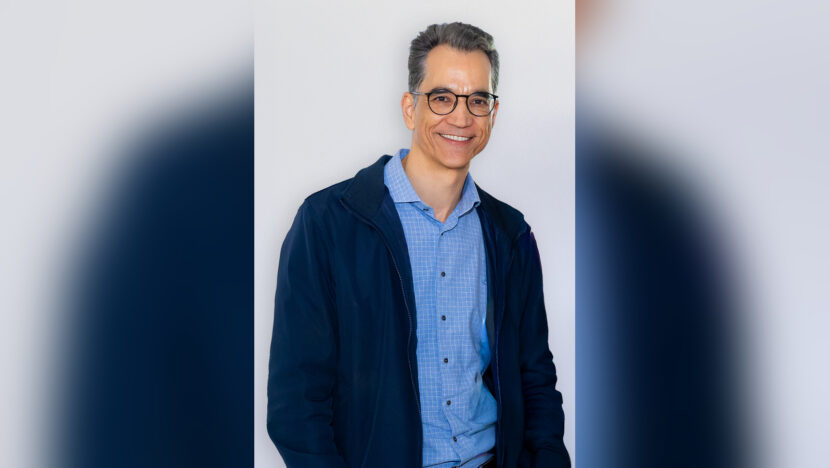 Lucas Guimarães, de óculos e camisa azul, posa sorrindo para a fotografia