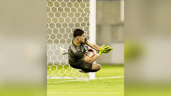 Goleiro Pedro Ytalo, com uniforme do QFC, salta para defender uma bola