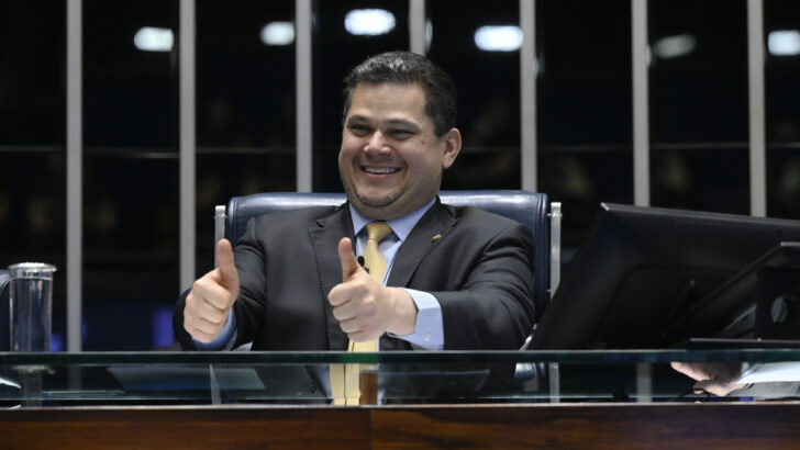 Davi Alcolumbre sentado no Senado, sorrindo e levantando os polegares