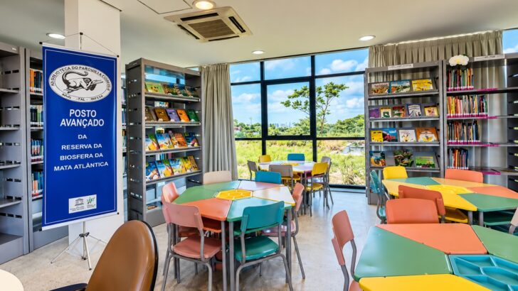 Mesas, cadeiras e estantes de livros no interior da Biblioteca do Parque da Cidade
