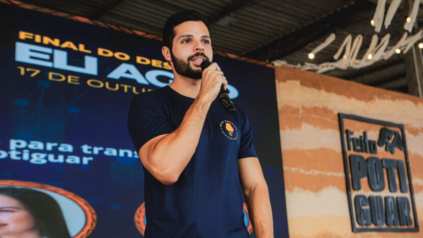 Participante fala ao microfone diante do painel da final do Desafio ELI Agro