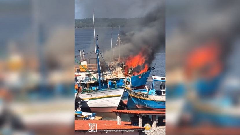 Barco azul em chamas entre embarcações atracadas no Rio Potengi, com fumaça escura