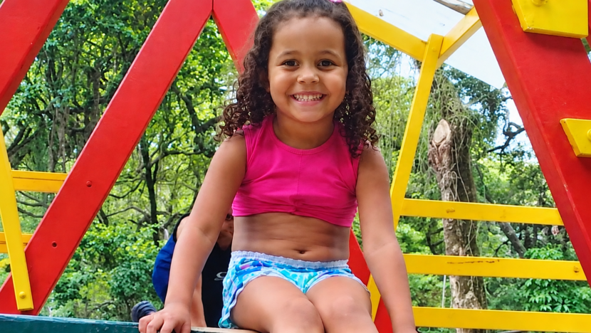 Ana Clara Gomes Machado sorrindo em brinquedo de parque