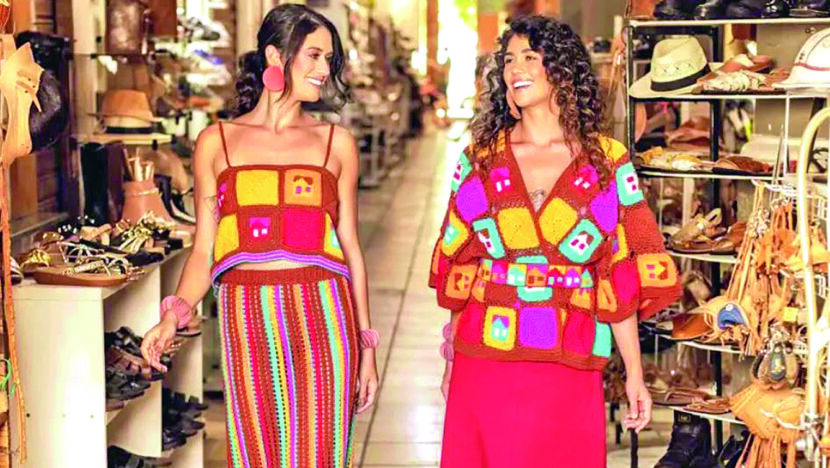 Modelos apresentam peças artesanais coloridas em ambiente de exposição
