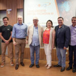 Participantes do lançamento do Tecnova III posam diante de painel do programa no Sebrae-RN em 2024