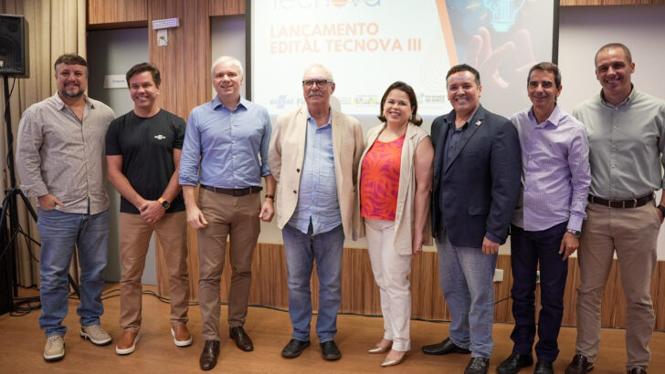 Participantes do lançamento do Tecnova III posam diante de painel do programa no Sebrae-RN em 2024
