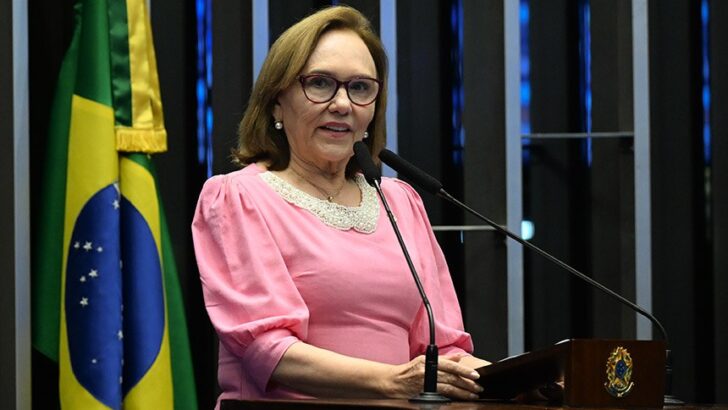 Zenaide Maia, de blusa rosa e óculos, discursa na tribuna do Senado, com a bandeira do Brasil ao fundo