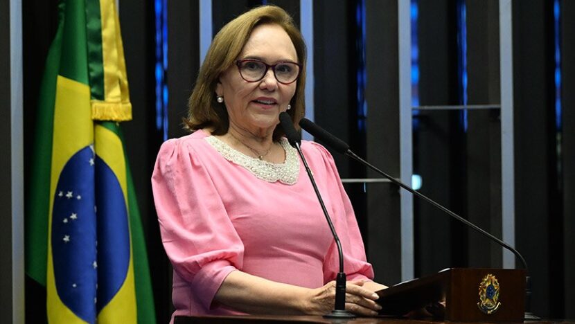 Zenaide Maia, de blusa rosa e óculos, discursa na tribuna do Senado, com a bandeira do Brasil ao fundo